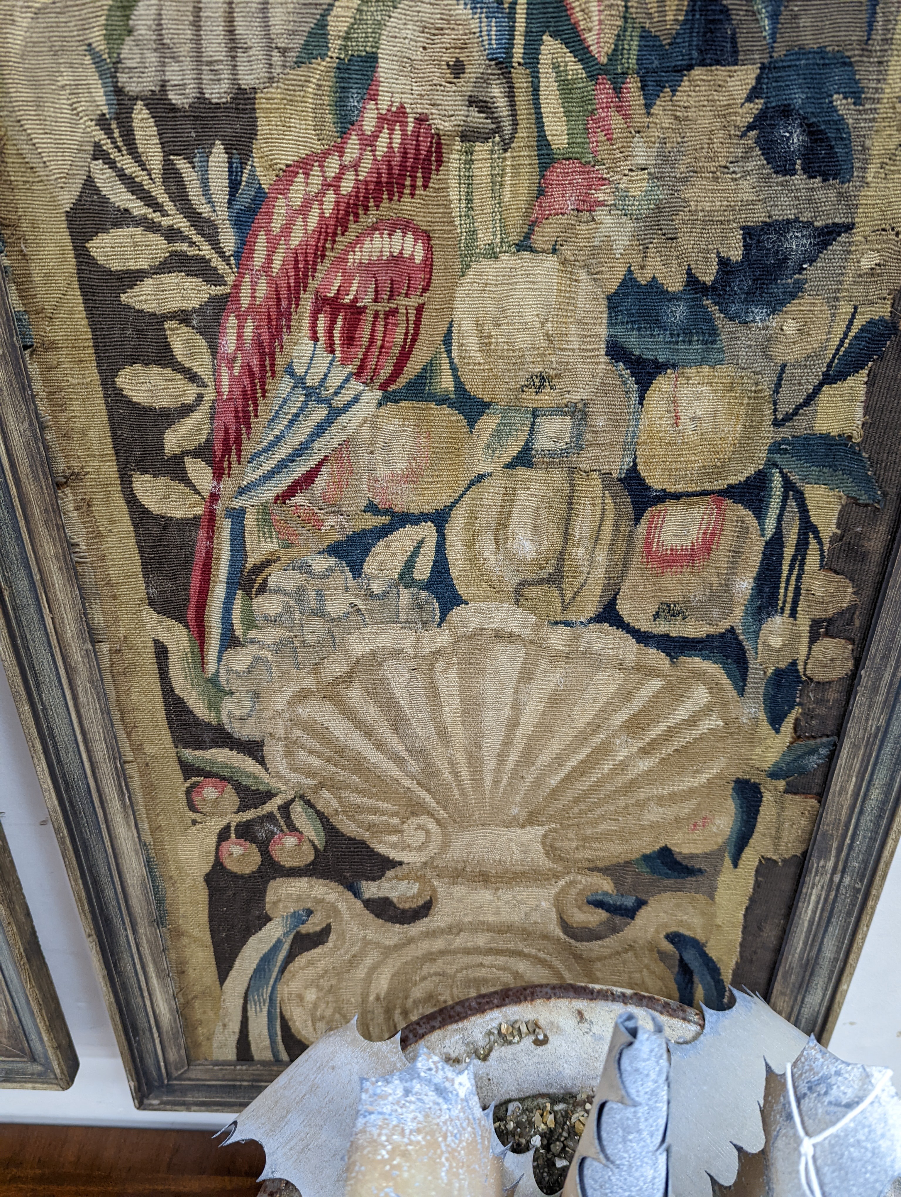 A pair of 17th century Mortlake tapestry panels of cherubs, circa 1660, with flowers, fruit and parrots, standing above scallop shells, later framed, 152 x 41cm, overall 161 x 50cm